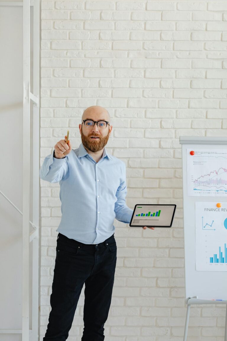 A businessman presents growth charts using a tablet and flipchart in an office setting.